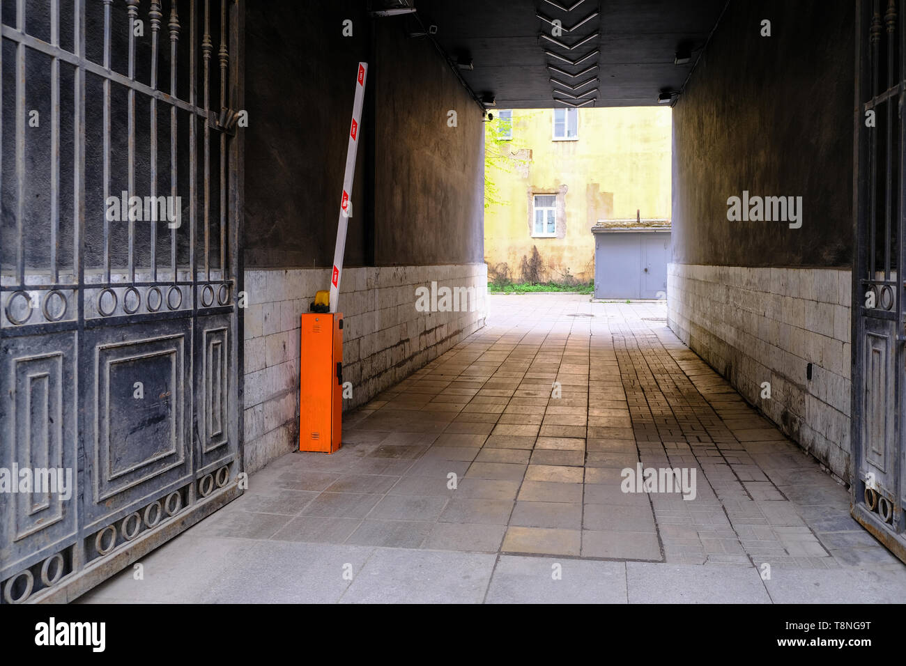 A dark alley with a massive gate. Automatic barrier Stock Photo