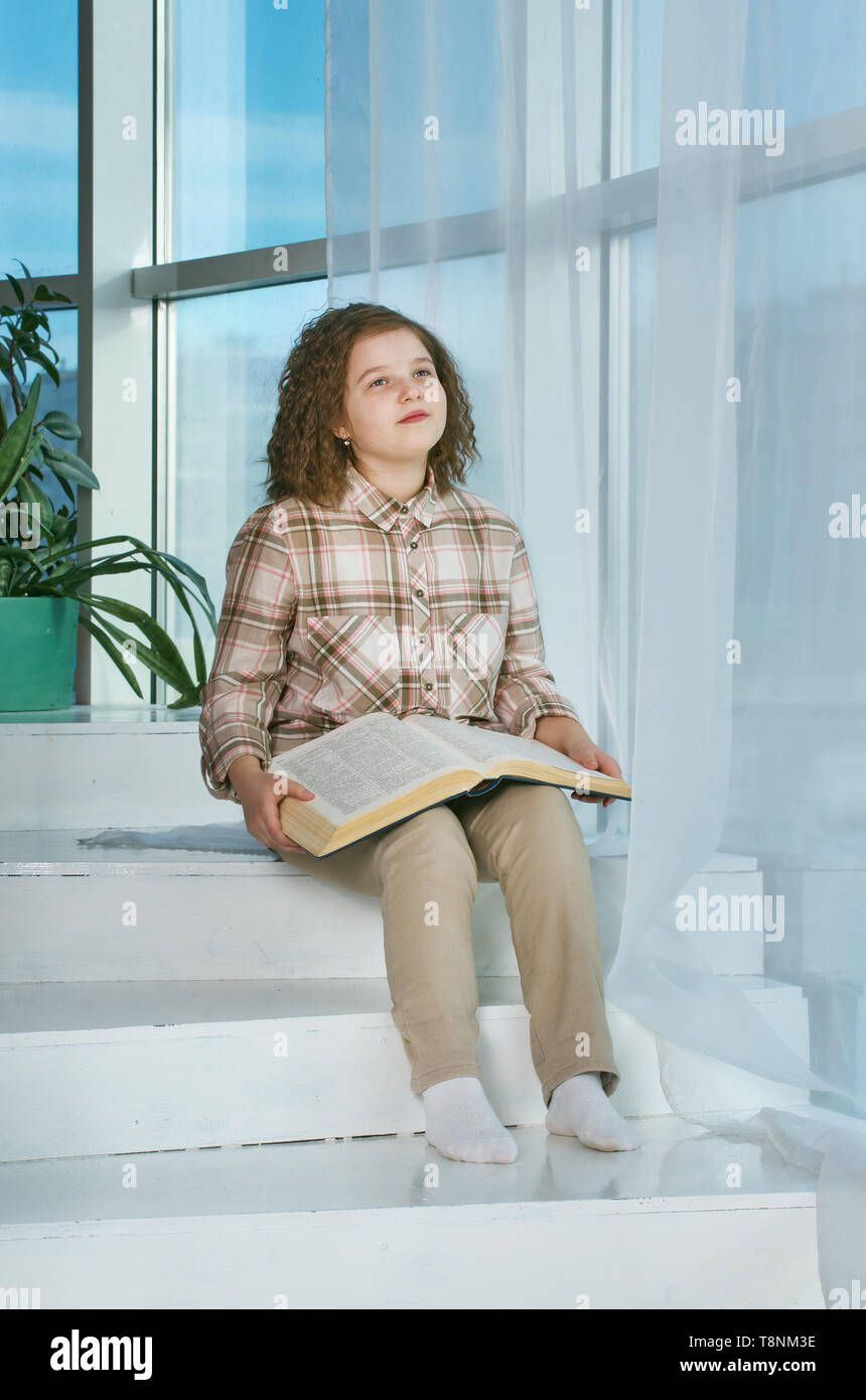 Cute little girl reading book at home Stock Photo - Alamy