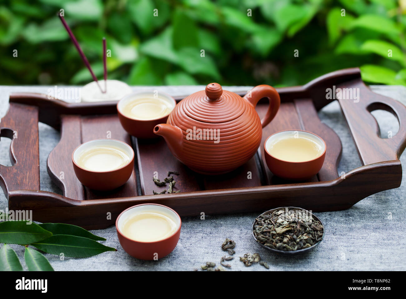 Green tea in tea pot and bowls, cups on a wooden tray. Outdoor