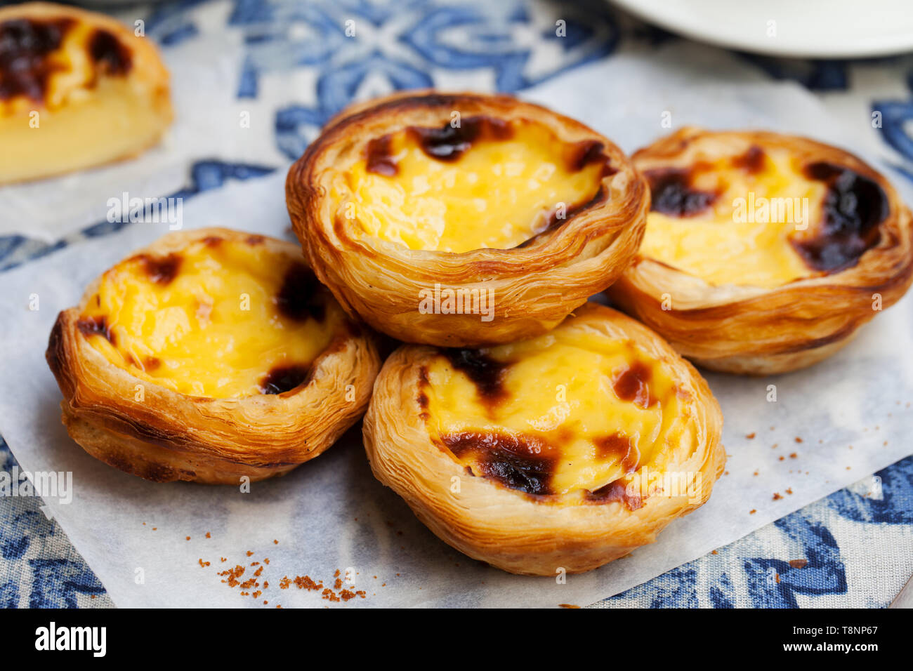 Egg tart, traditional Portuguese dessert, pastel de nata on a plate. Blue textile background. Stock Photo