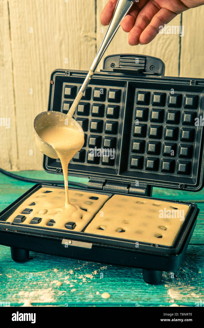 Making wafers at home. Pouring the dough into the waffle iron Stock Photo Alamy