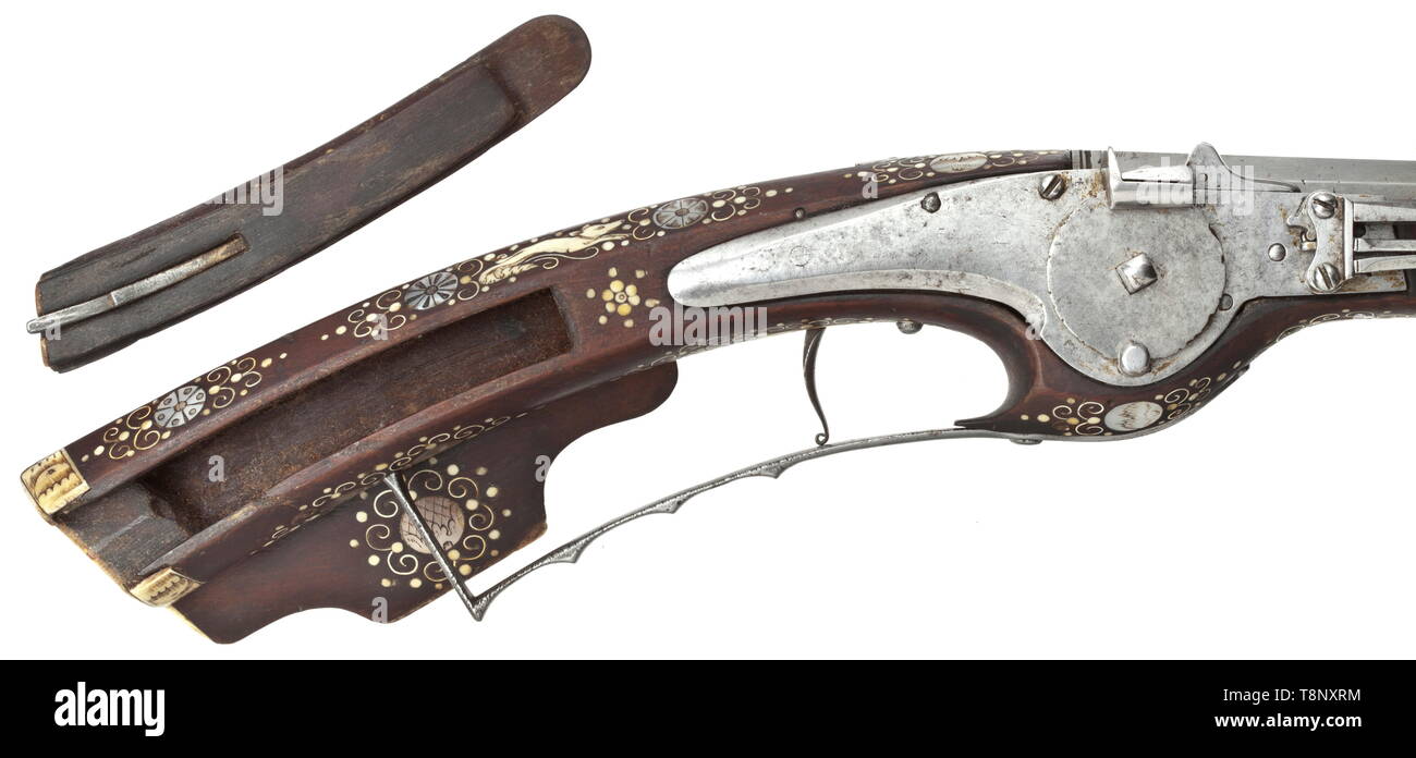A Silesian wheellock petronel, circa 1630 Smooth two-stage barrel in 13 mm calibre, octagonal then round, with iron front sight and brass rear sight. At the breech a silver-filled mark 'HS' above heart (Stöckel no. 3112). Smooth wheellock with mark on the inside 'MS' (Stöckel no. 4044). Walnut full stock, lavishly inlaid with bone and engraved mother-of-pearl, with bone nose. On the cheek engraved St. George with the dragon, the side opposite the lock with Nereid playing the lute, the patch-box with an engraved elephant and a winged monster. Wood, Additional-Rights-Clearance-Info-Not-Available Stock Photo