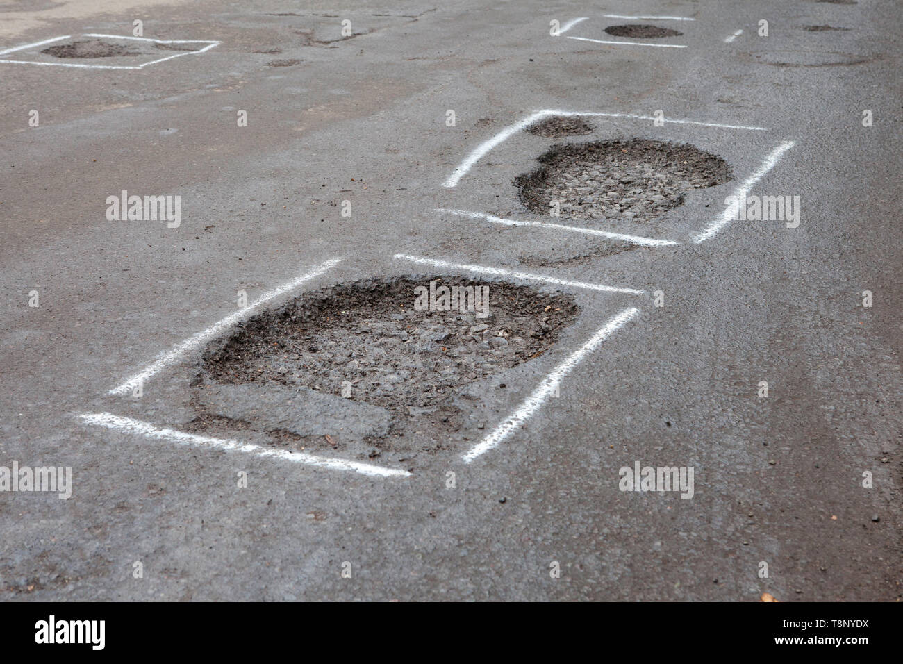 Potholes in a road marked for repair with paint Stock Photo