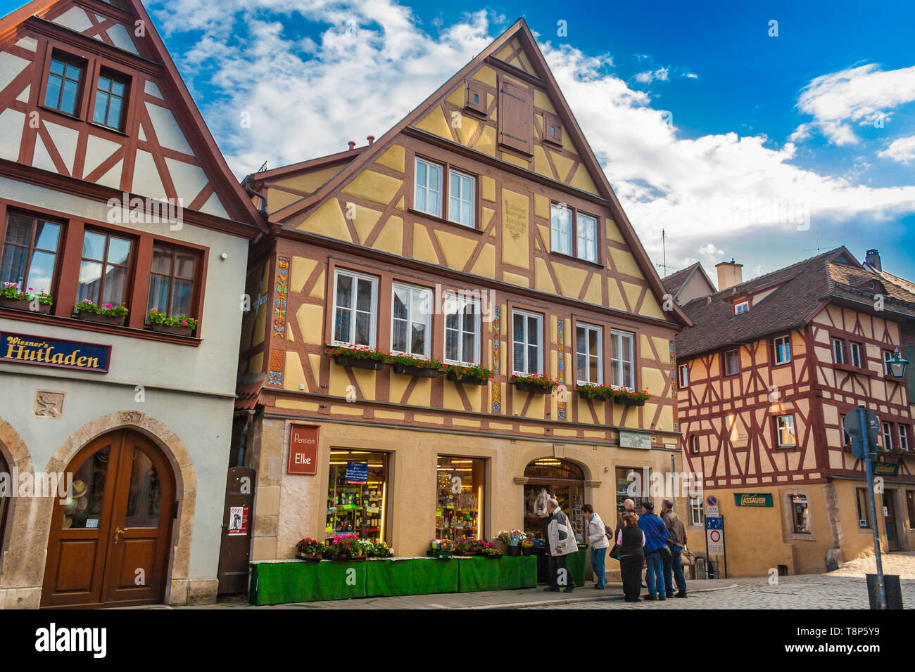 Picturesque view of a row of colourful half-timbered houses and shops with people in front on a cobblestone street in the medieval town Rothenburg ob... Stock Photo