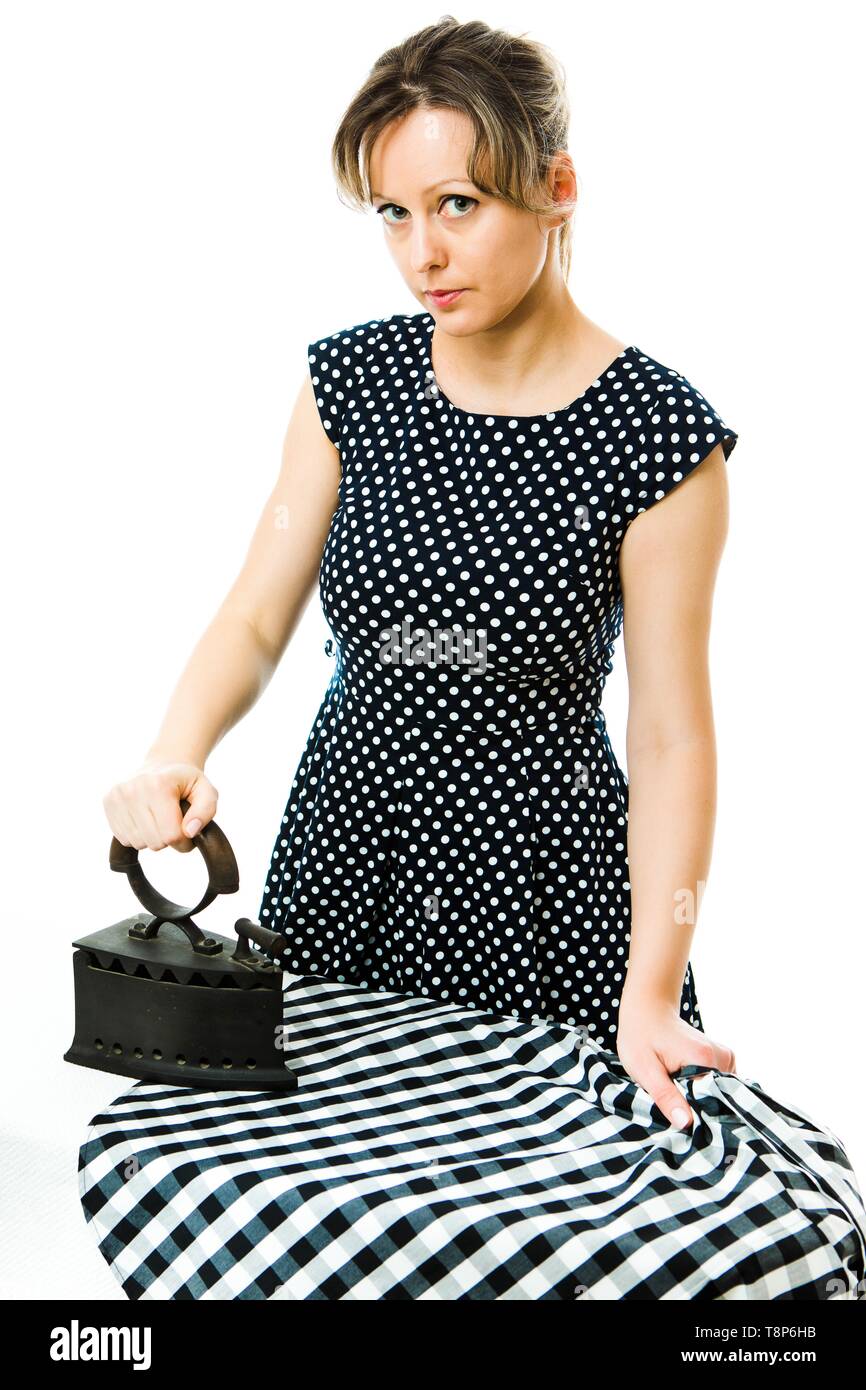 Attractive housewife ironing with vintage coal metal ironing tool - concept on white background Stock Photo