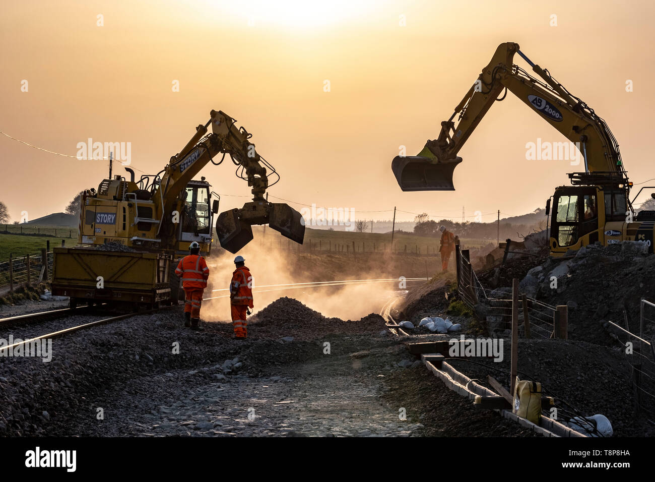 Railway workers constructing railway and finishing shift at sunset Stock Photo
