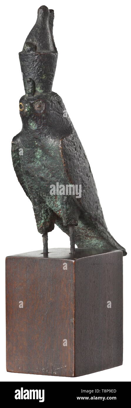 An ancient Egyptian statuette of the Horus falcon, Late Period, mid- to 2nd half of the 1st millennium BC Bronze falcon with double crown. The circular gold inlay of the right eye has been preserved. The surface slightly corroded, therein visible the lines of the former chiselling to depict the plumage. The talons and the lower parts of the legs are broken off. On a modern wooden base. Height without base 15 cm. Appealing, expressive small-scale sculpture. Provenance: 1970s private collection from the Munich areas. historic, historical, ancient w, Additional-Rights-Clearance-Info-Not-Available Stock Photo