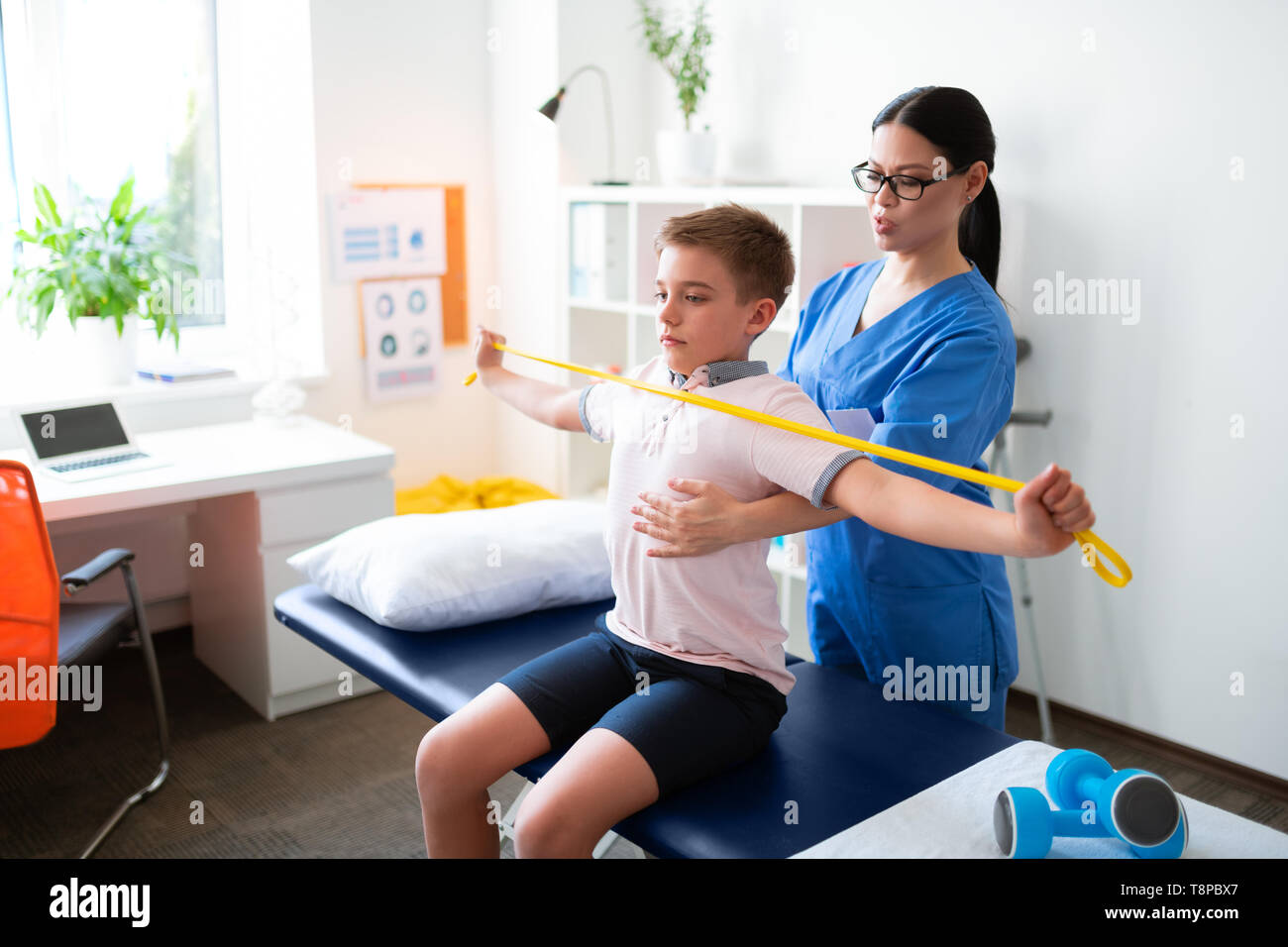 Professional physical therapist gently helping little boy with