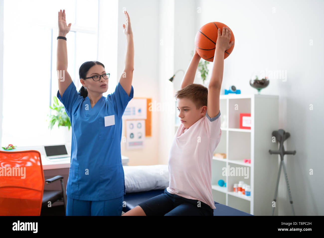 Serious professional physical therapist raising her hands Stock Photo