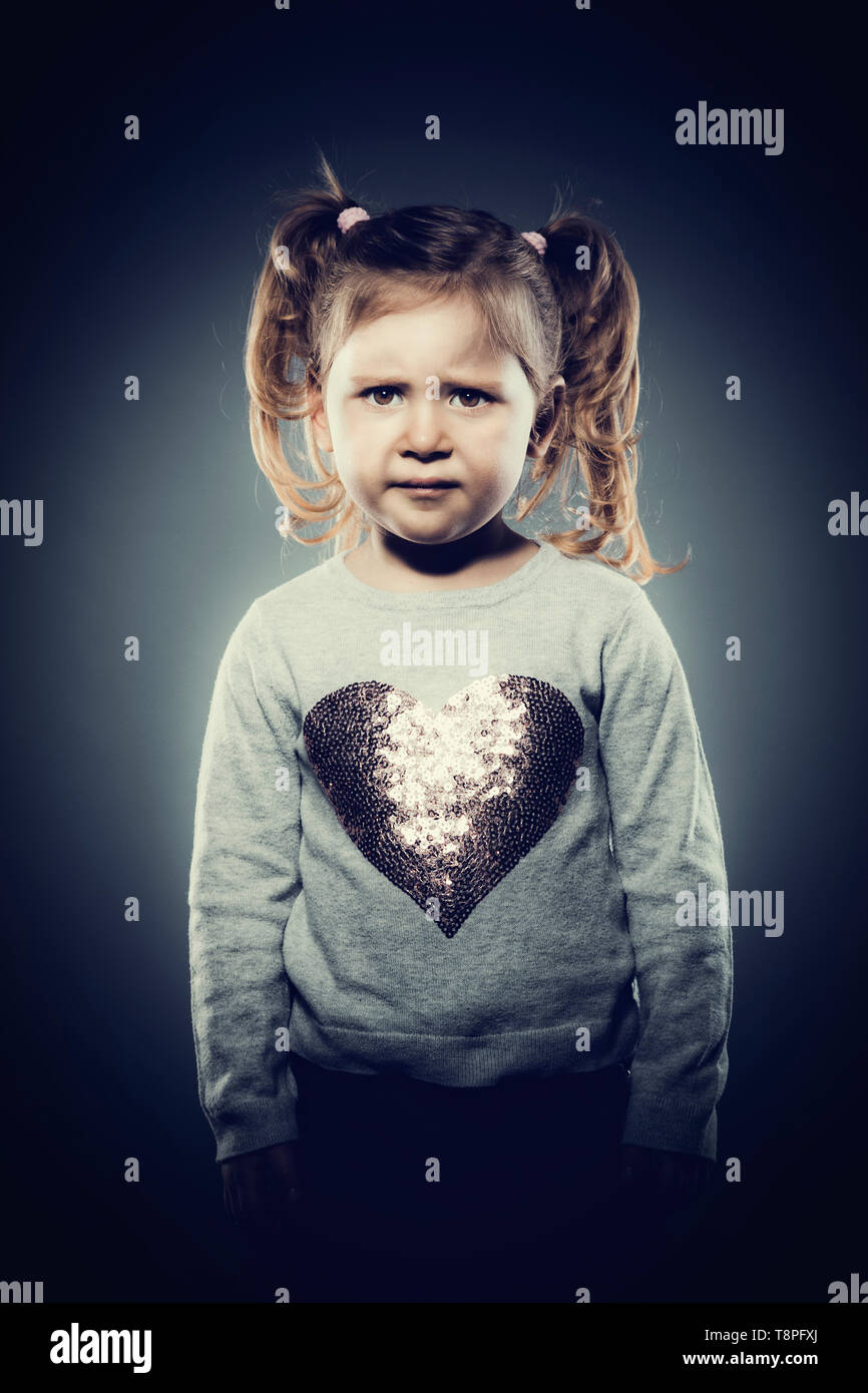 studio portrait of a 3 year old girl with a sad expression, looking directly at the camera. Stock Photo