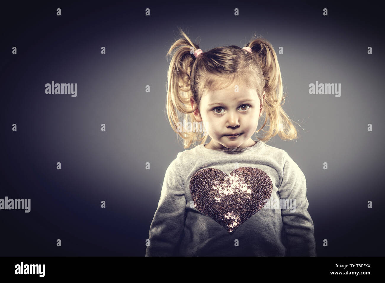 portrait of a 3 year old Caucasian girl with pigtails, studio shot, neutral look at the camera. Stock Photo