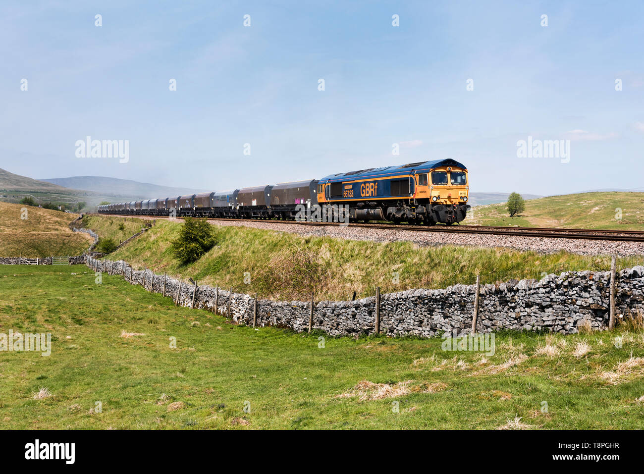 A train with a load of stone from Arcow Quarry, near Horton-in-Ribblesdale, heads south past Selside on the Settle-Carlisle railway. Stock Photo