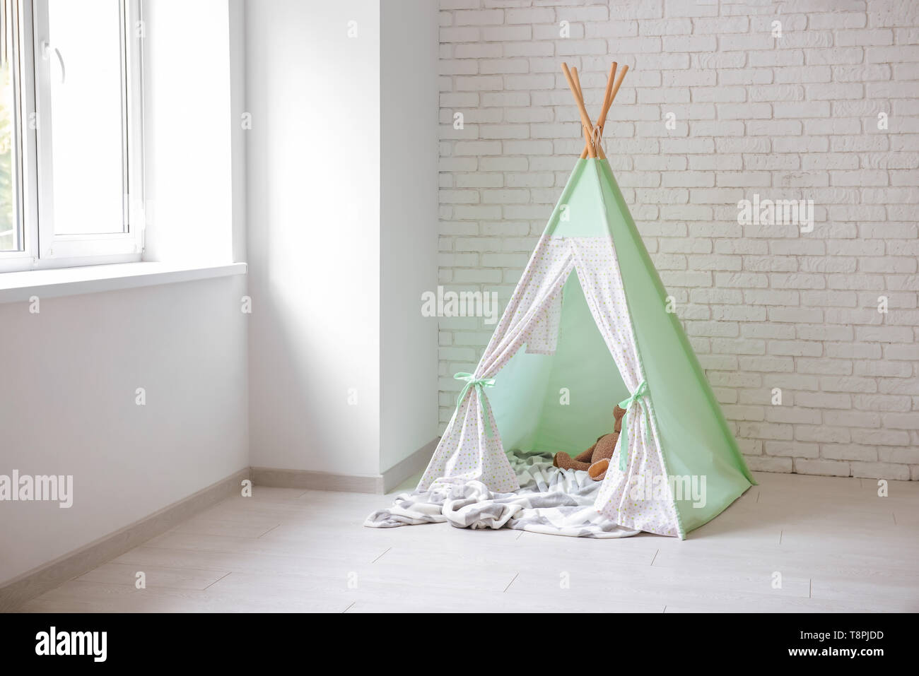 Cozy play tent for kids near white brick wall indoors Stock Photo