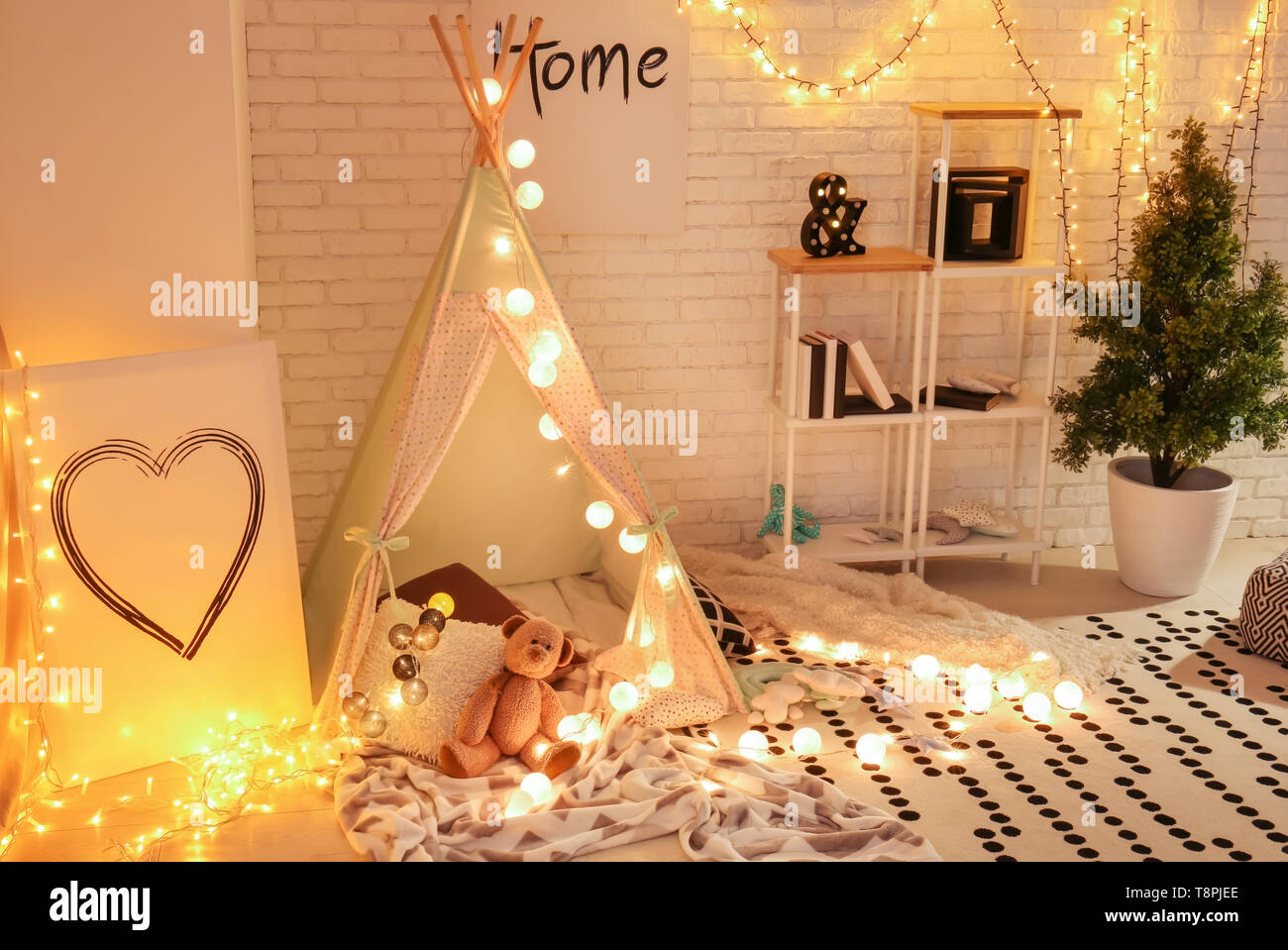 Cozy play tent for kids with glowing garland in room interior Stock Photo