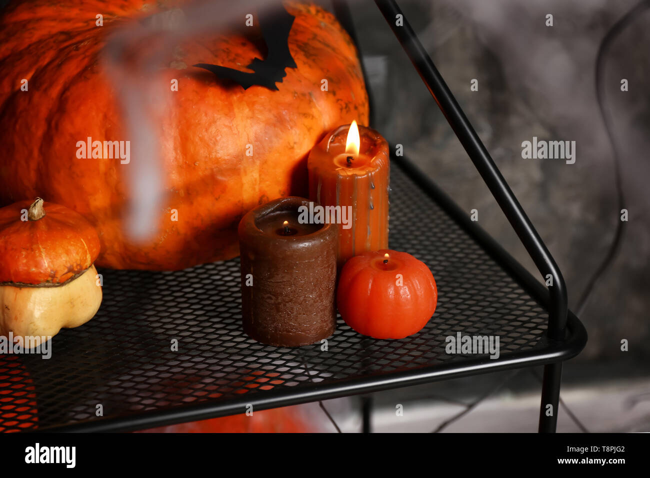 Burning candles with pumpkins as decor for Halloween party on stand ...