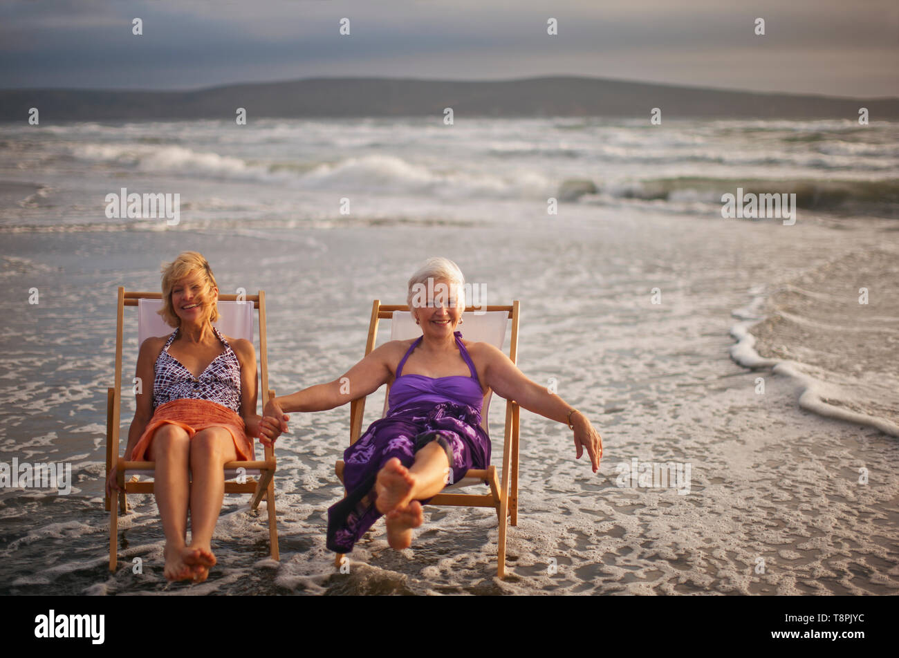 Two happy mature women relaxing in deck chairs on the beach Stock Photo ...