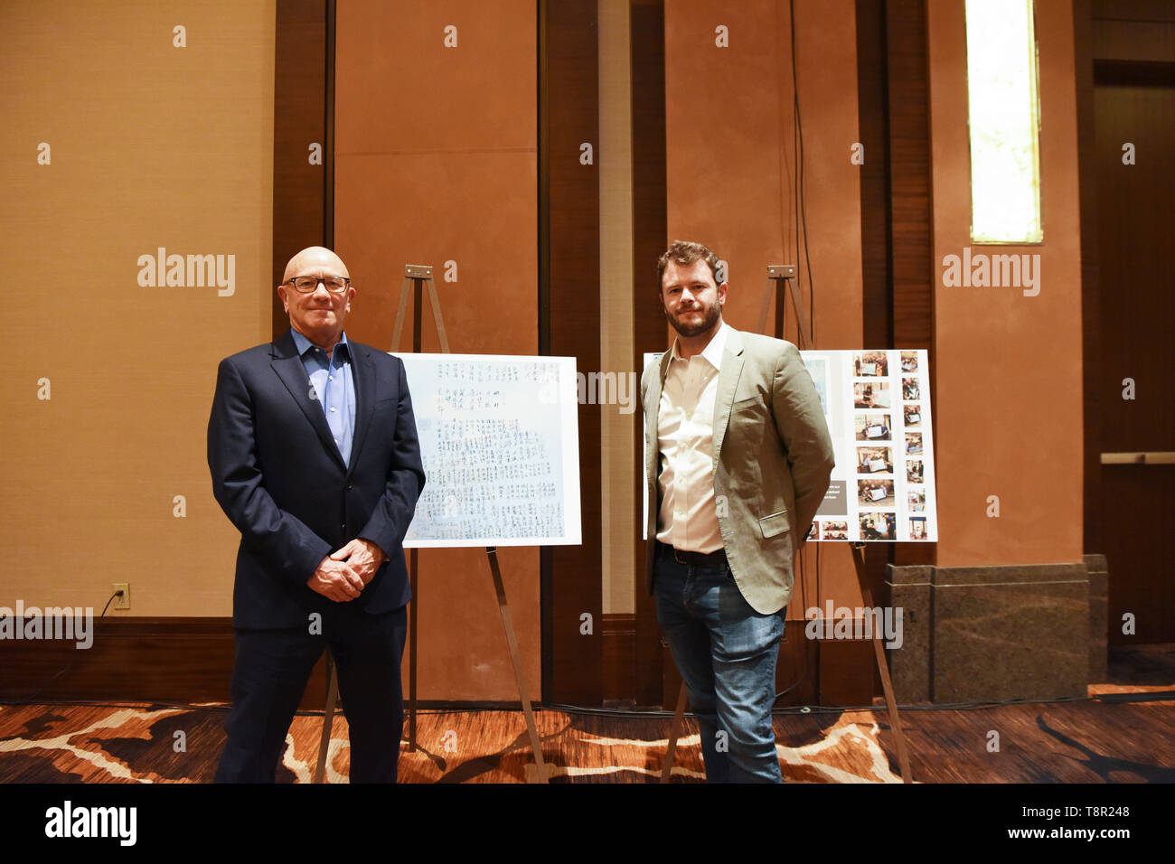 (190514) -- NEW YORK, May 14, 2019 (Xinhua) -- James Bryant (L) and his son Ben Bryant pose in front of the memorial posters at the 4th Sino-American Second World War Friendship and Flying Tiger History Conference in Las Vegas, the United States, May 11, 2019. James Bryant will never forget the day when his 93-year-old father went back to his bedroom and came back with a flight brief case containing papers related to the training and assignments he took as a U.S. Flying Tiger pilot during the World War II. As a 'remarkable' yet 'humble' man and a loving father, James E. Bryant did not show an Stock Photo