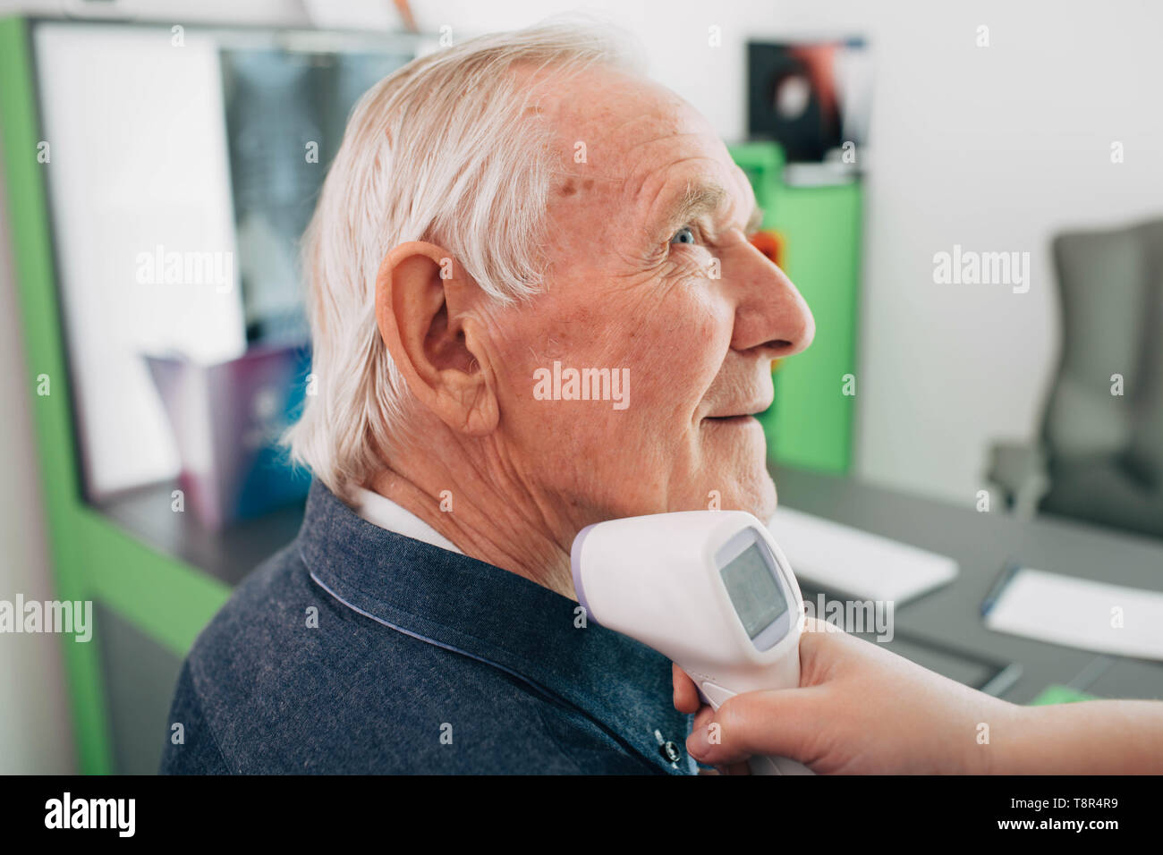 Nurse taking a senior patient's temperature with a digital thermometer. Stock Photo