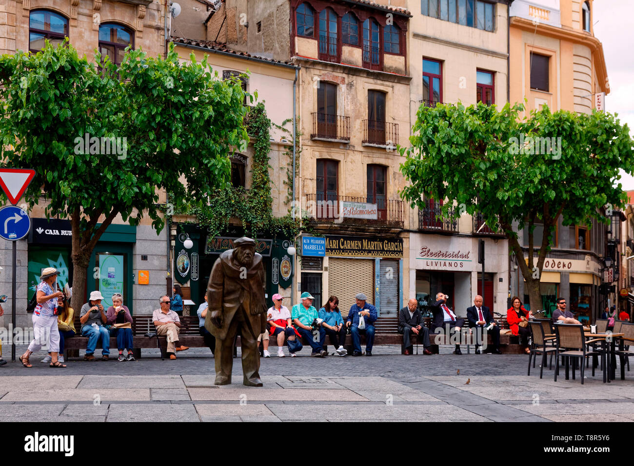 city scene; people sitting, statue, old buildings, shops, table, chairs; UNESCO site; Europe; Salamanca; Spain; spring, horizontal Stock Photo