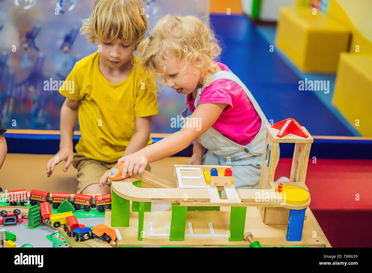 Children playing with wooden train. Toddler kid and baby play with
