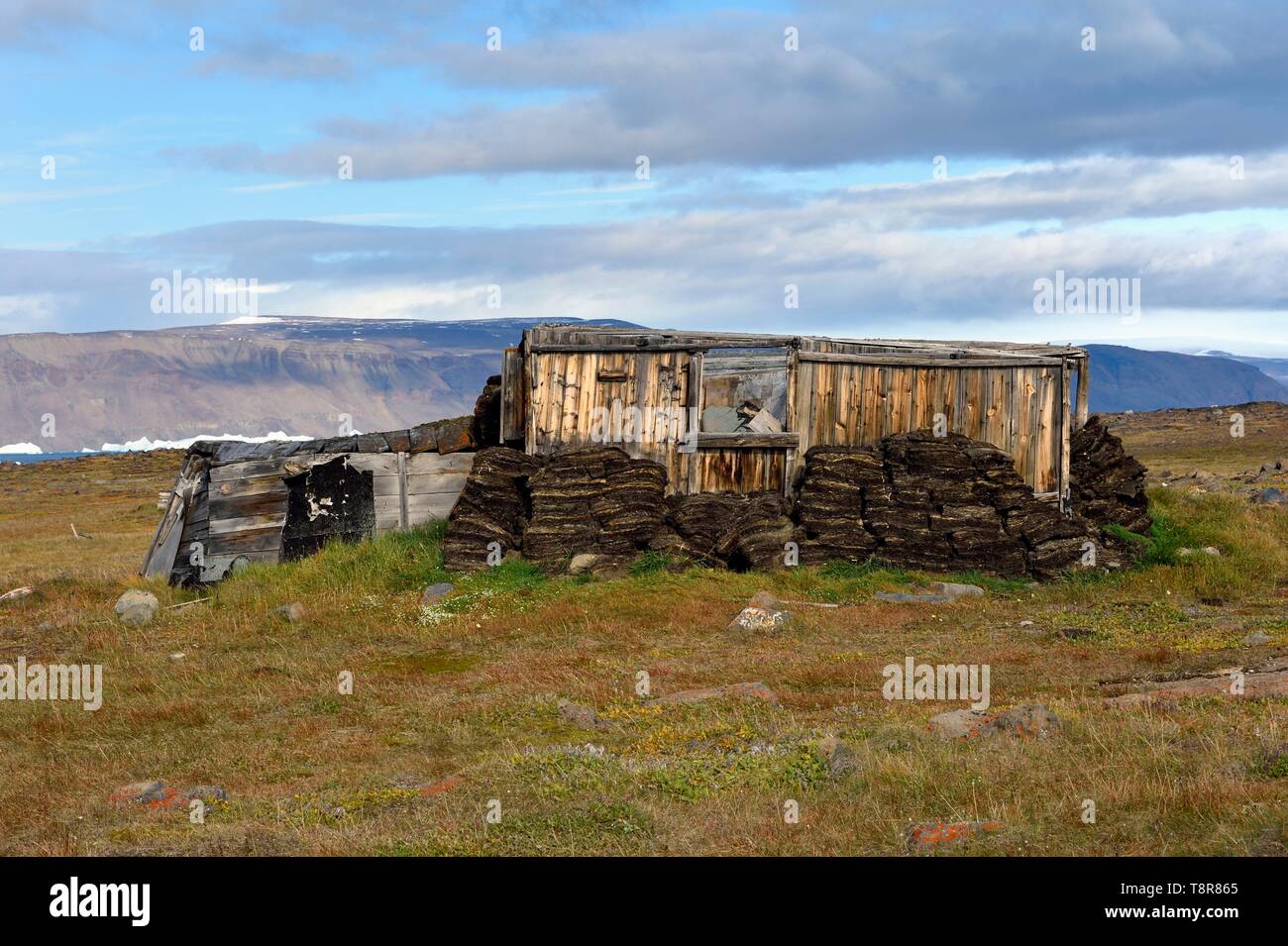 Greenland, West Coast, North Star Bay, Wolstenholme fjord, Dundas (Thule), Inuit Igloo, traditional house with peat walls and, from the beginning of the 20th century, an internal wooden structure, the ice cap in the background Stock Photo