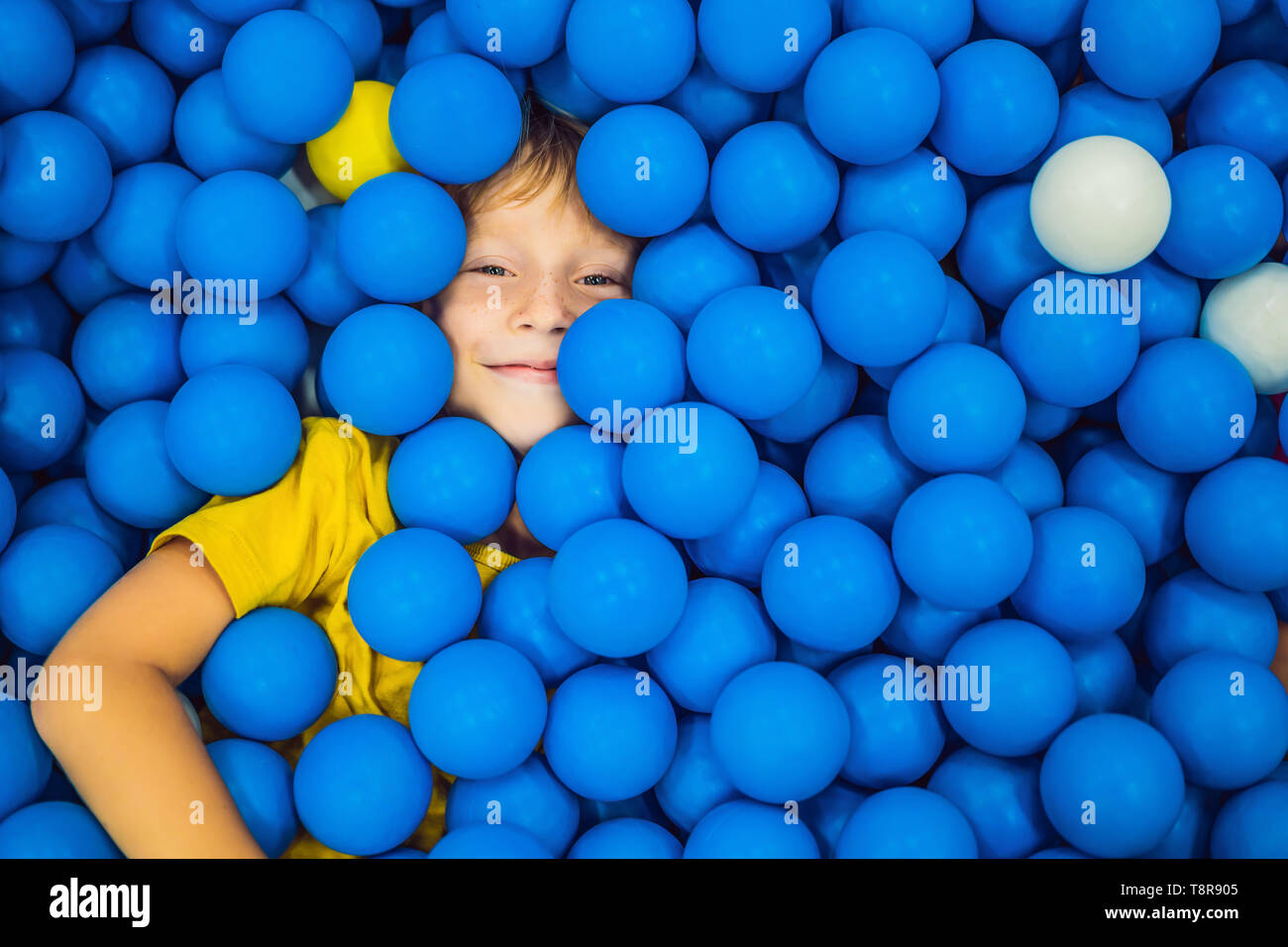 Child playing in ball pit. Colorful toys for kids. Kindergarten or preschool play room. Toddler kid at day care indoor playground. Balls pool for Stock Photo