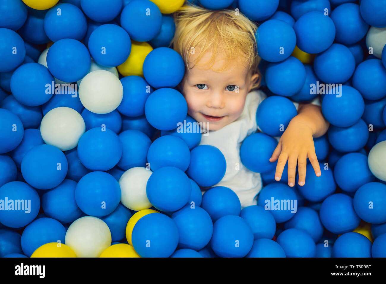 Child playing in ball pit. Colorful toys for kids. Kindergarten or preschool play room. Toddler kid at day care indoor playground. Balls pool for Stock Photo