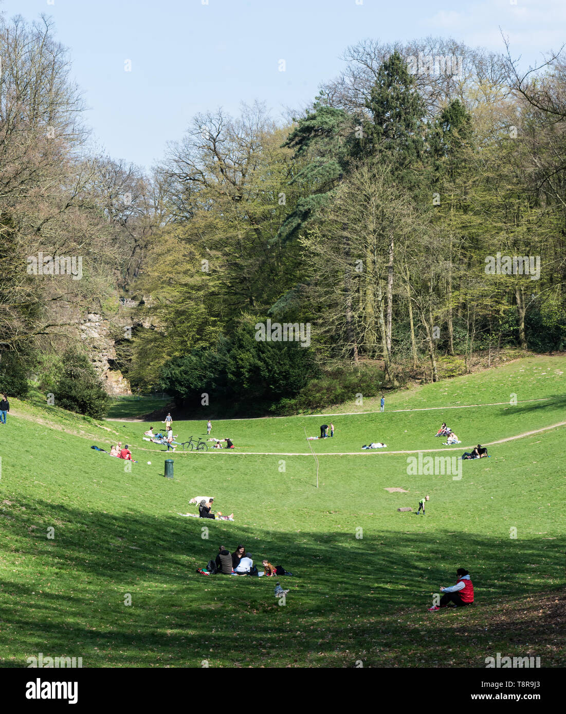 Ixelles, Brussels/ Belgium - 03 30 2019: Mixed group of people walking and restinging at the green lawns of the Bois de La Cambre city park during a s Stock Photo