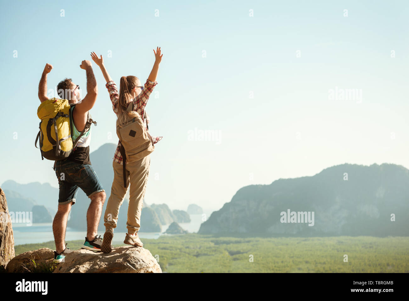 Two happy tourists stands with raised arms on viewpoint Stock Photo