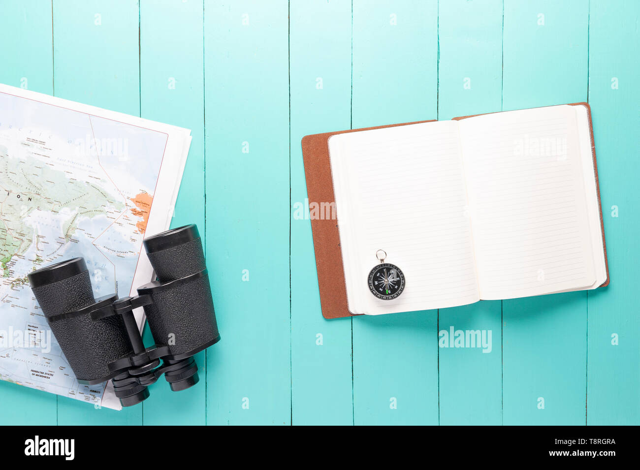 Top view of binocular, world map, compass and notebook on green wood background, travelling concept, plan a trip, Itinerary planner. Stock Photo