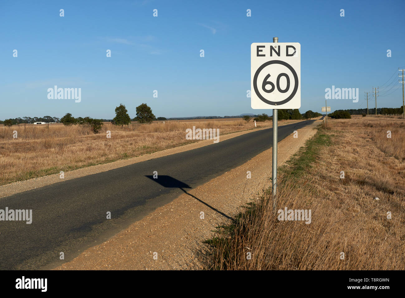 End of speed restriction road sign on a narrow Australian country road signifying an end to a 60 kilometre per hour safety speed limit area. Stock Photo