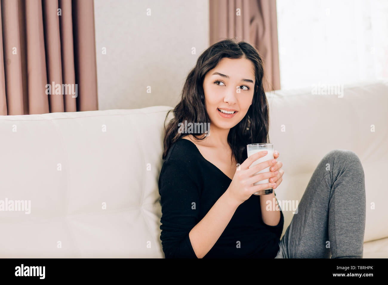Cheerful Brunette Student Relaxing Sitting On Cozy Sofa Holding