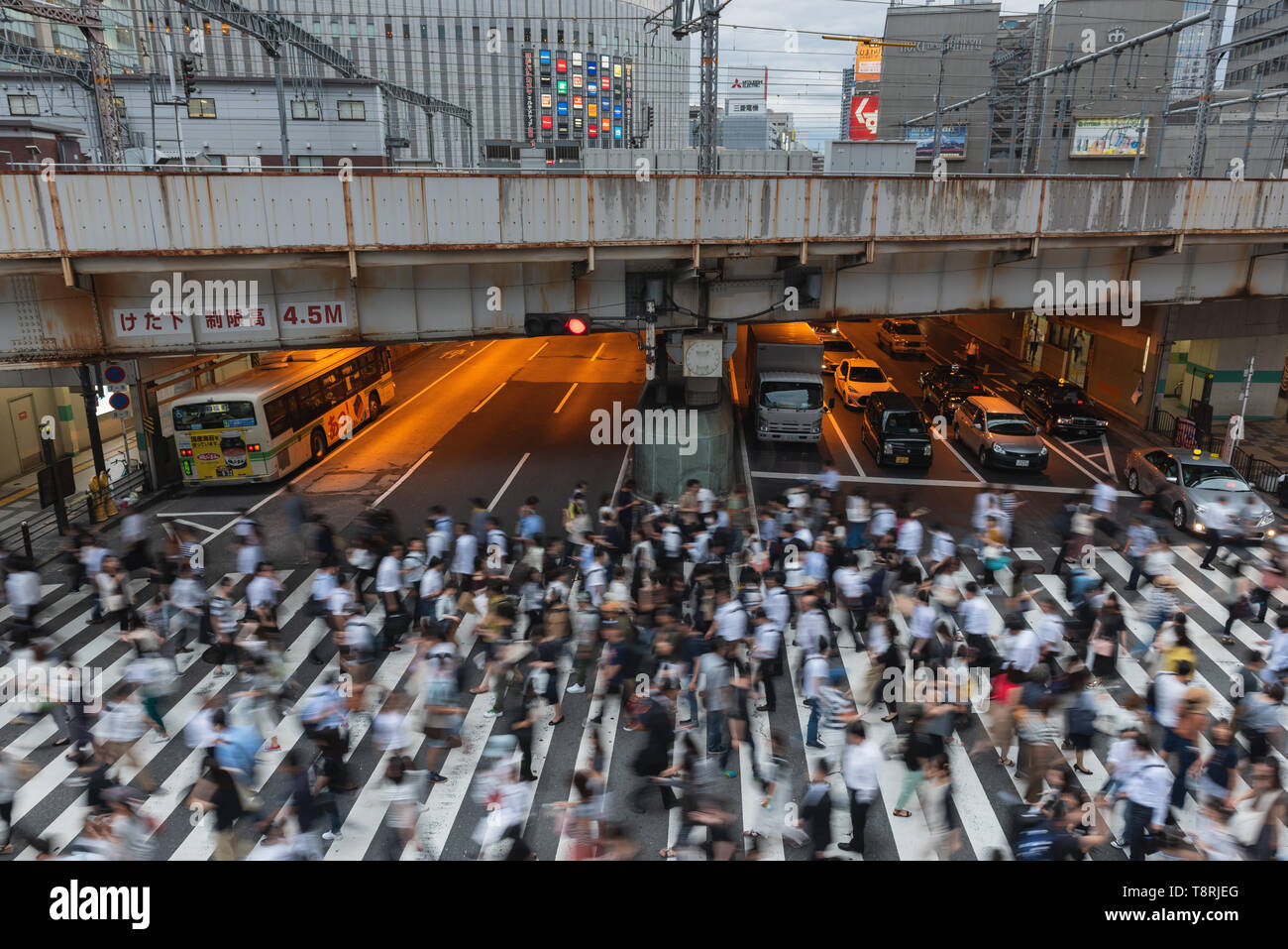 Pedestrians cross an intersection in the Shibuya district of Tokyo, Japan. Stock Photo