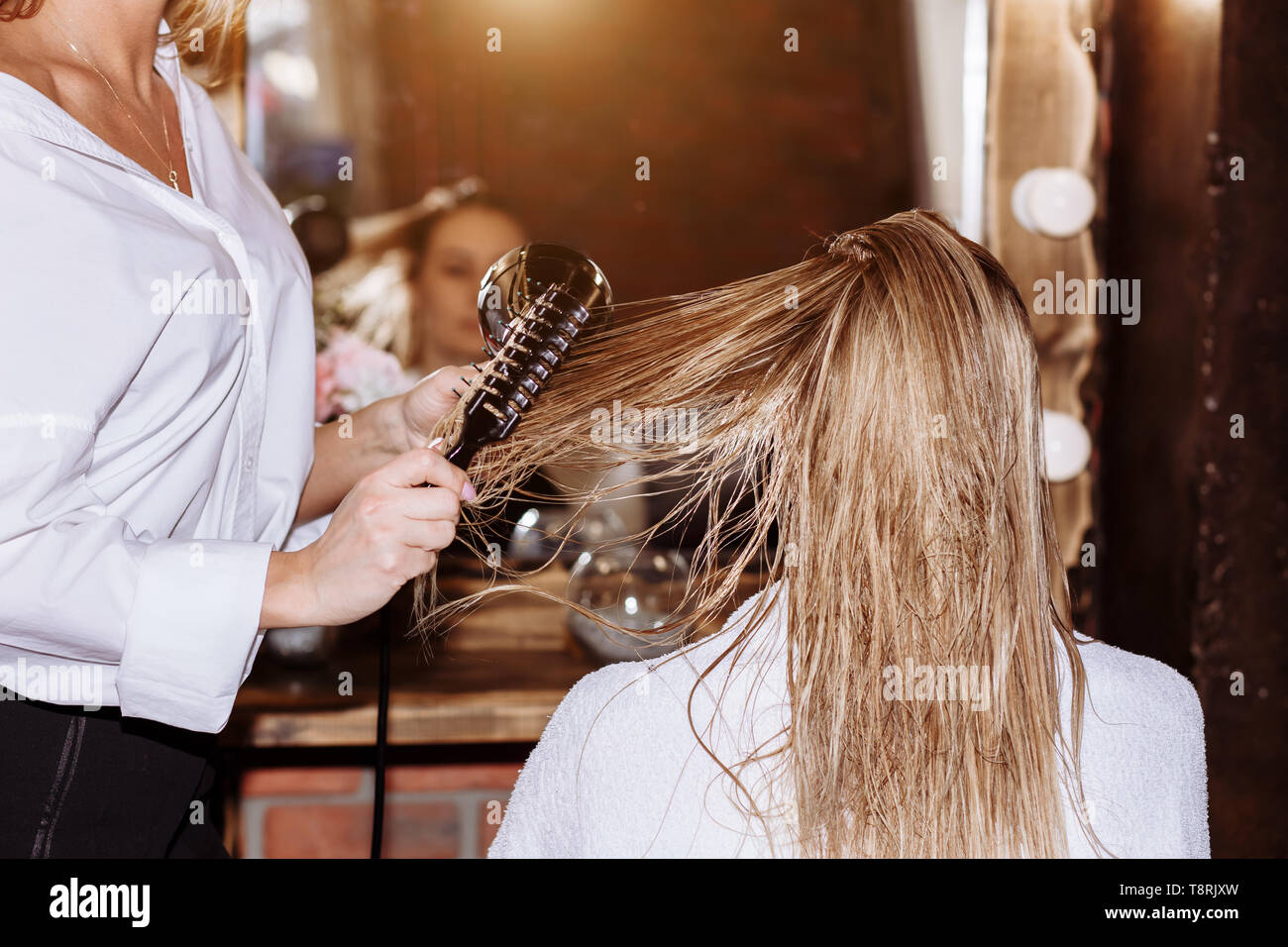 Close up of professional hairdresser using brush and hairdryer styling