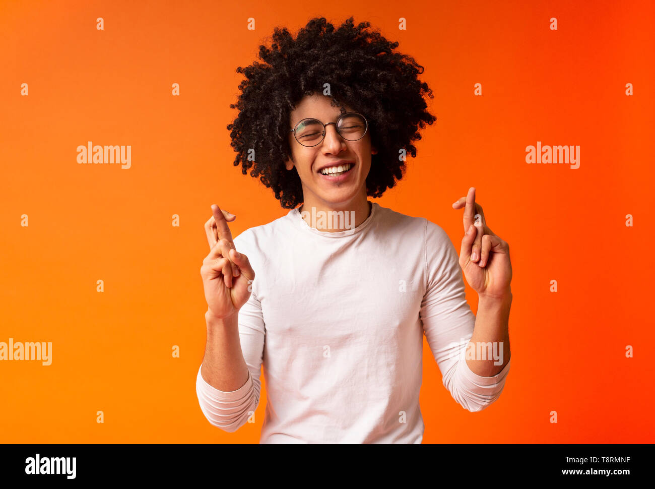 Cheerful Black Guy Crossing Fingers For Luck Stock Photo