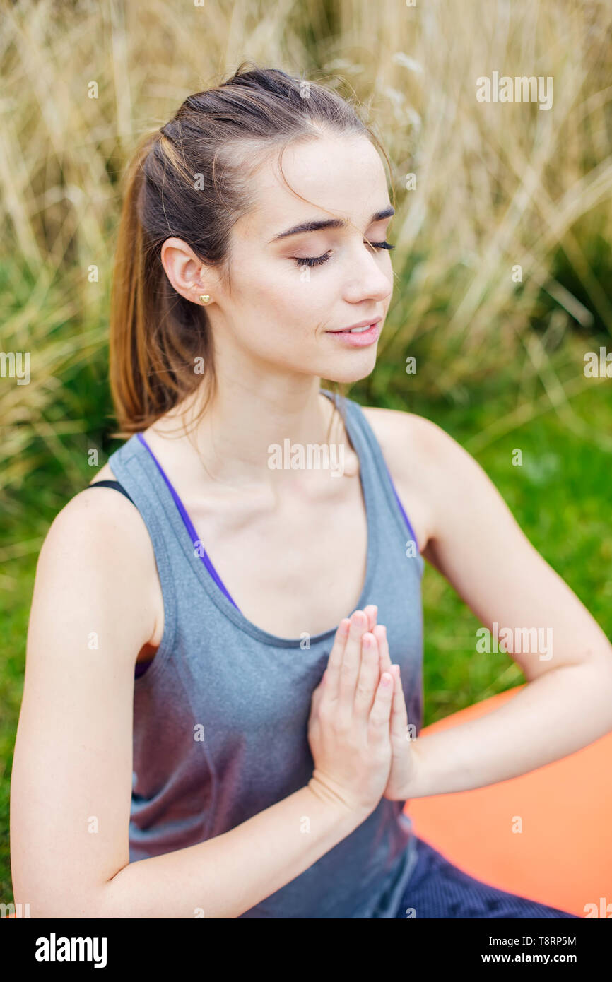 Pretty young woman practices yoga and meditates in the lotus position ...