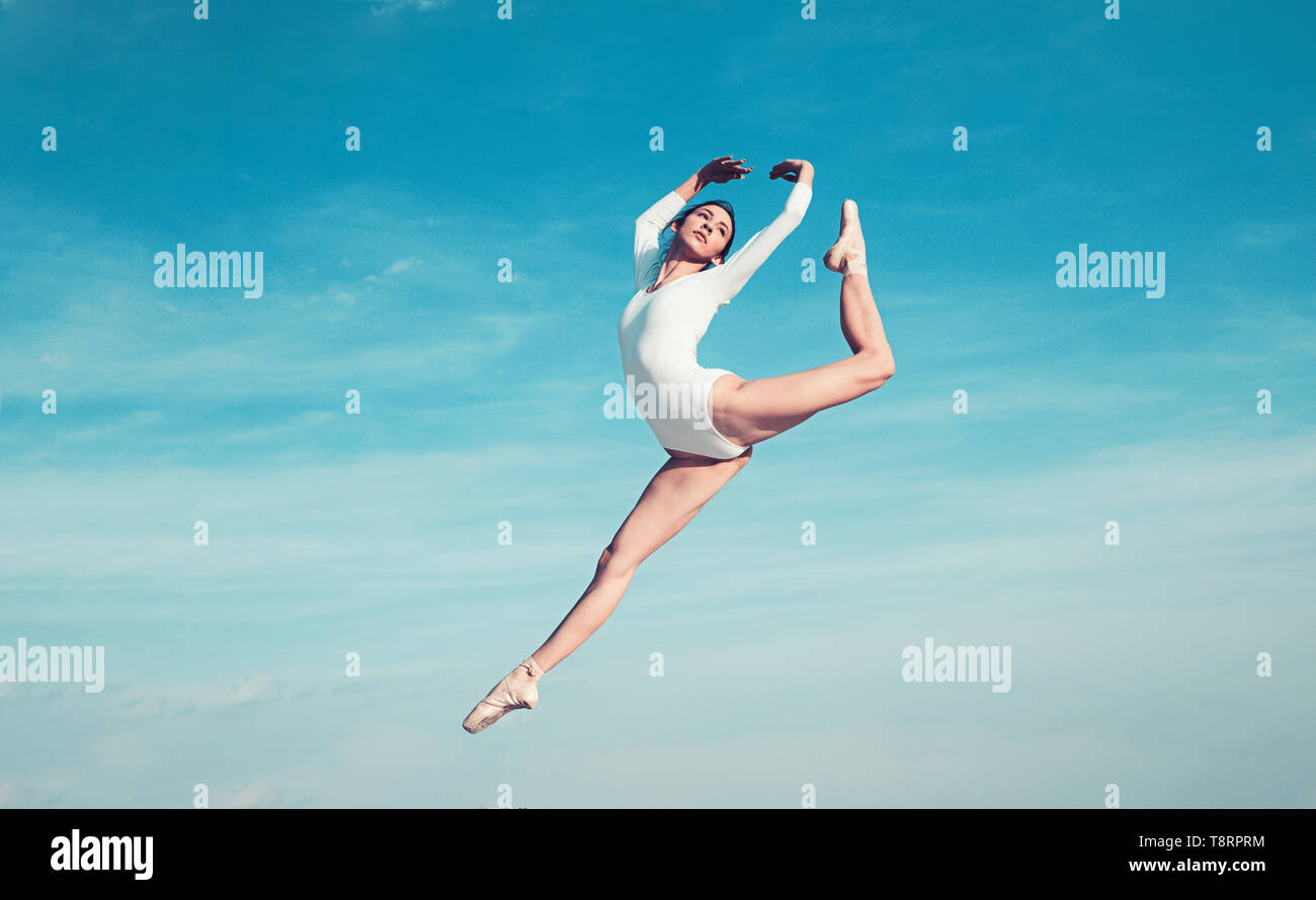 Feels like flying. Young ballerina jumping on blue sky. Pretty girl in dance wear. Cute ballet dancer. Concert performance dance. Practicing art of Stock Photo