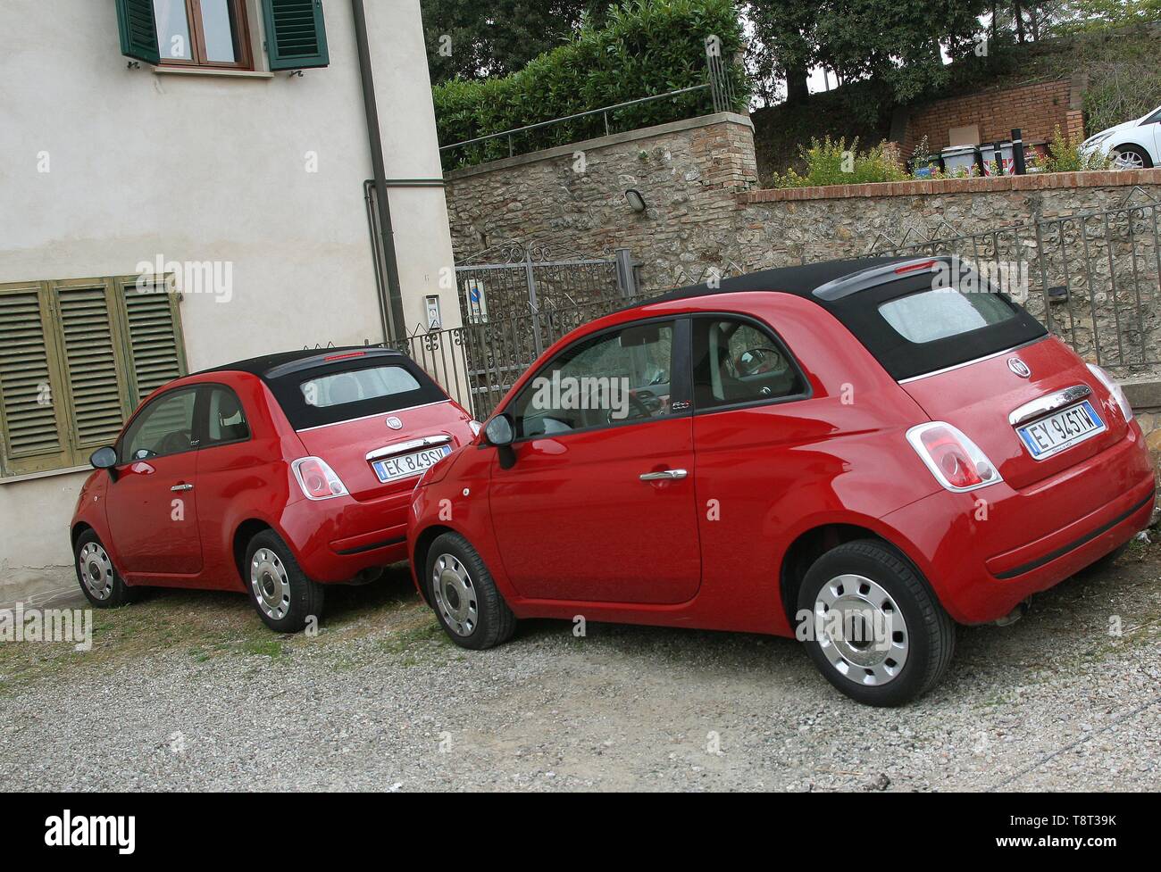 Two Identical red Fiat 500 parked on a house driveway in the hilltop ...