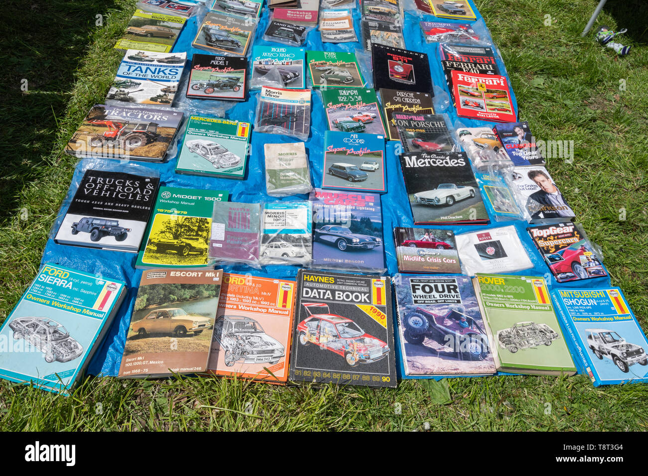 Haynes manuals and other books about cars and vehicles laid out on the ground for sale on a trade stand at a UK car show Stock Photo