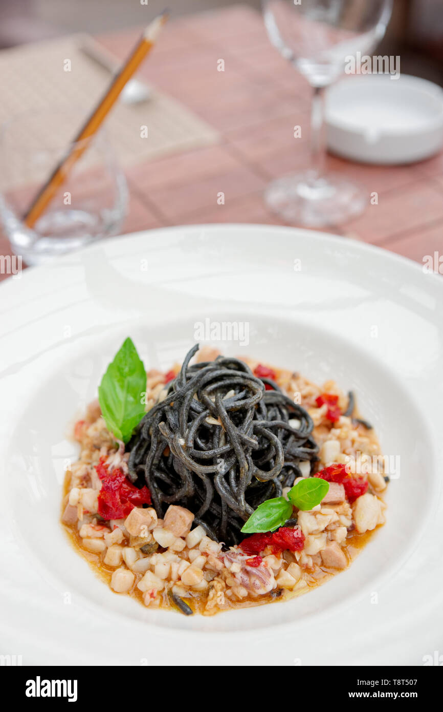 Black squid ink pasta with seafood on table Stock Photo