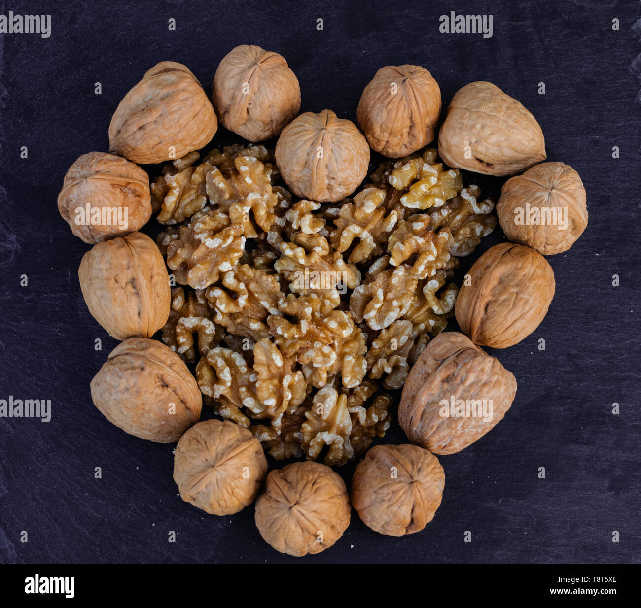 Walnuts, with and without shell, heart shaped, on black surface Stock Photo