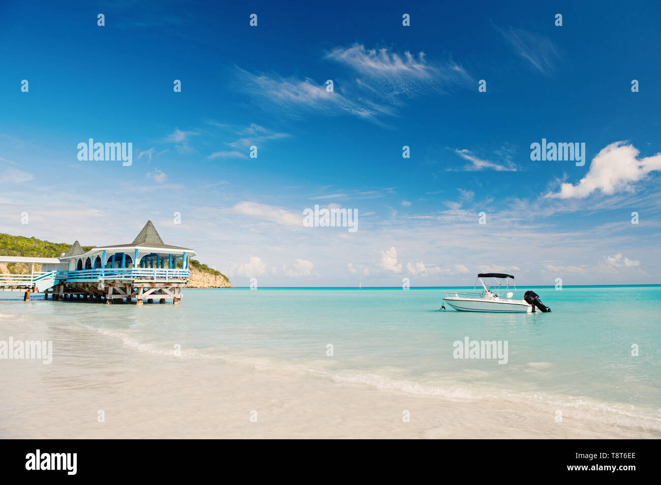 Enjoy benefits being beside sea. Sea turquoise water bungalow and ship near beach. Vacation sea sand beach tropical house bungalow st.johns antigua. Idyllic sunny day at seaside blue sky. Stock Photo