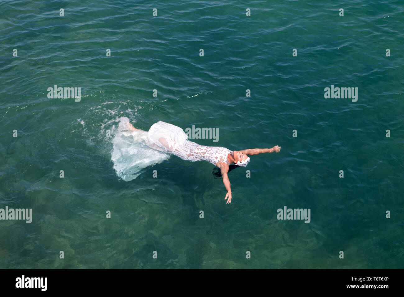Bride white wedding dress lay sea water. Wet wedding dress hot sunny
