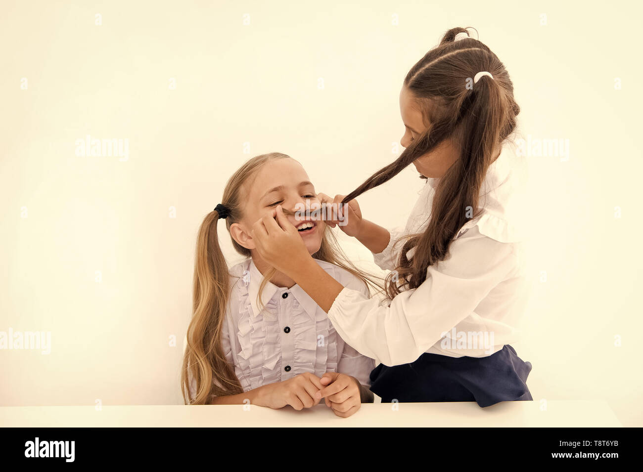 Girls make mustache with long hair. Lets imagine you were boy. Girl  cheerful playful mood play with hair as mustache. Masculinity and femininity  concept. Hairstyle fashion. Schoolgirls tidy uniforms Stock Photo -