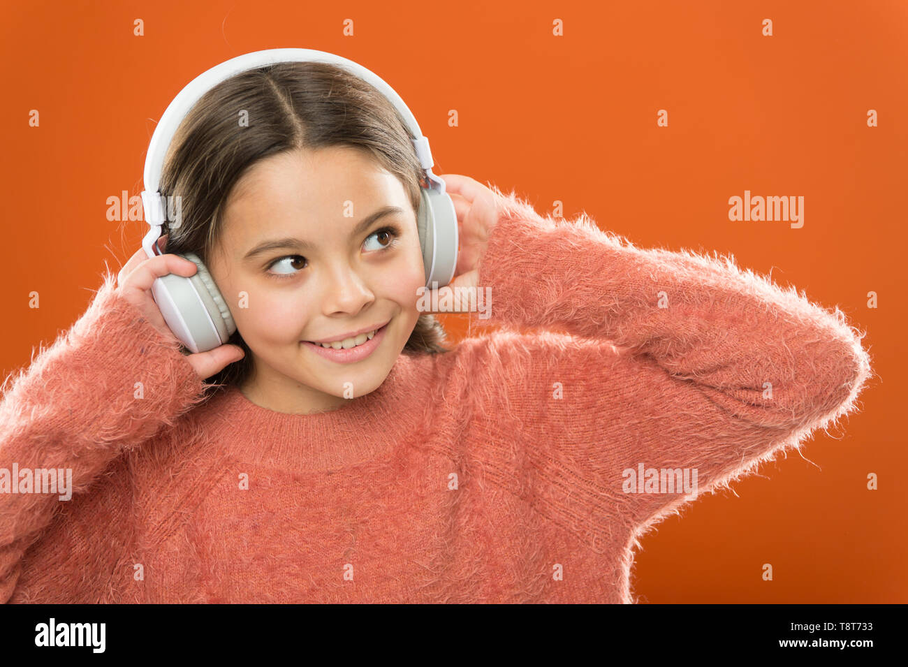 Modern technology is amazing. Small child wearing headphones with bluetooth technology. Little girl listening to music with wireless earphones. Stereo sound technology. Technology and music. Stock Photo
