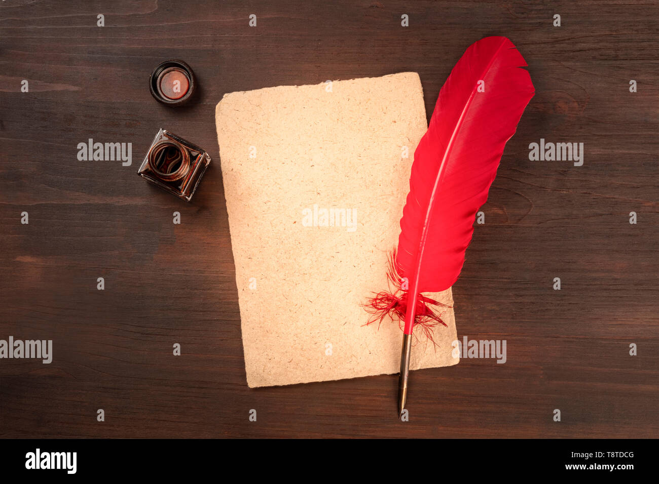 A vintage background with a quill pen on a piece of old parchment paper, with an ink well, shot from above on a dark wooden background Stock Photo