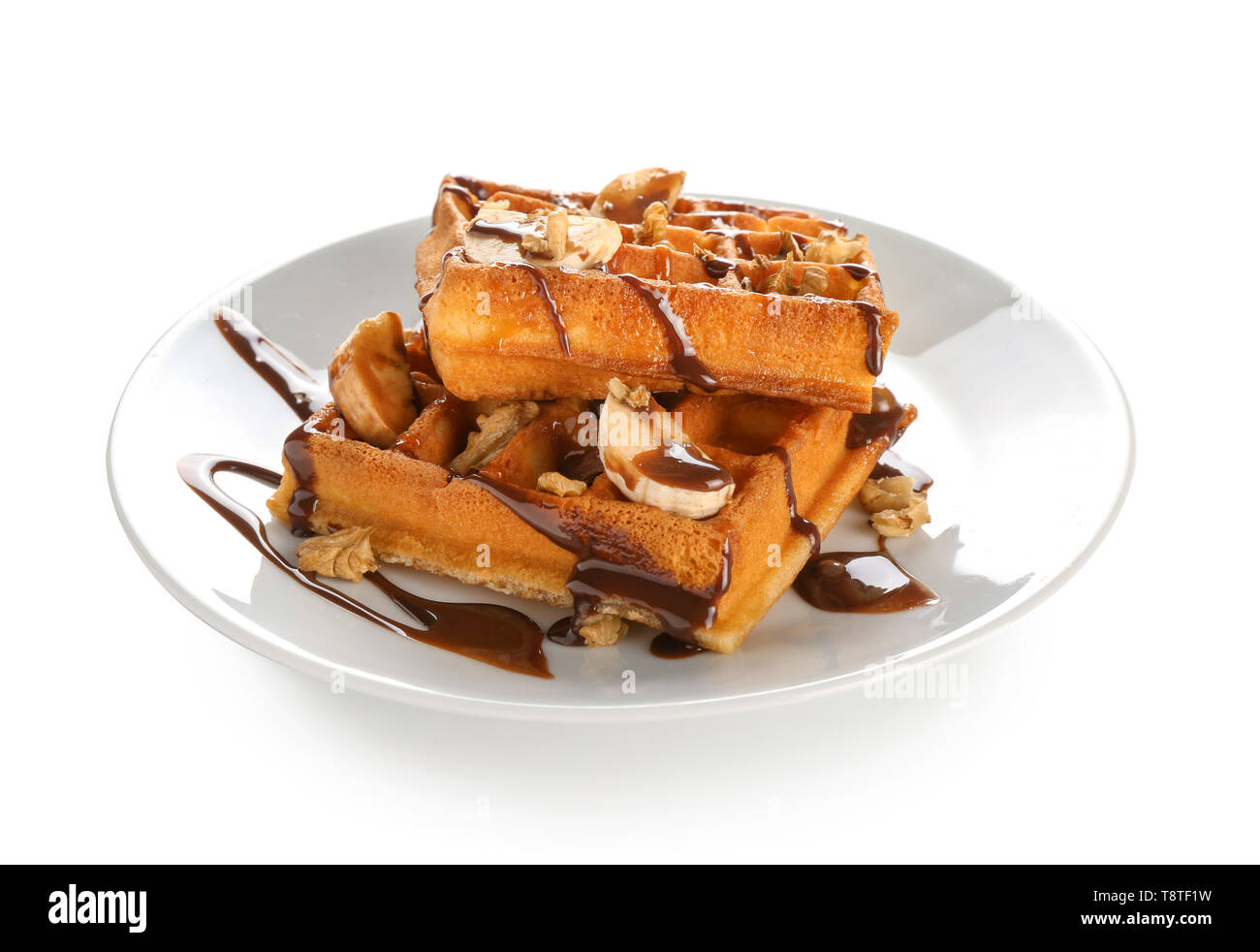 Delicious waffles with banana slices and chocolate sauce on white ...