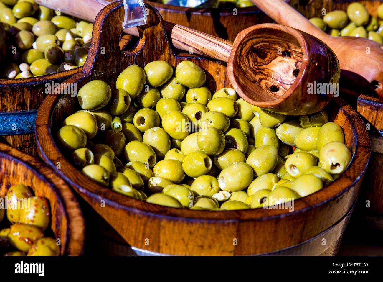Fresh green olives in a wooden bucket and ladle at a farmer's market (Victoria Park Market, London, UK) Stock Photo