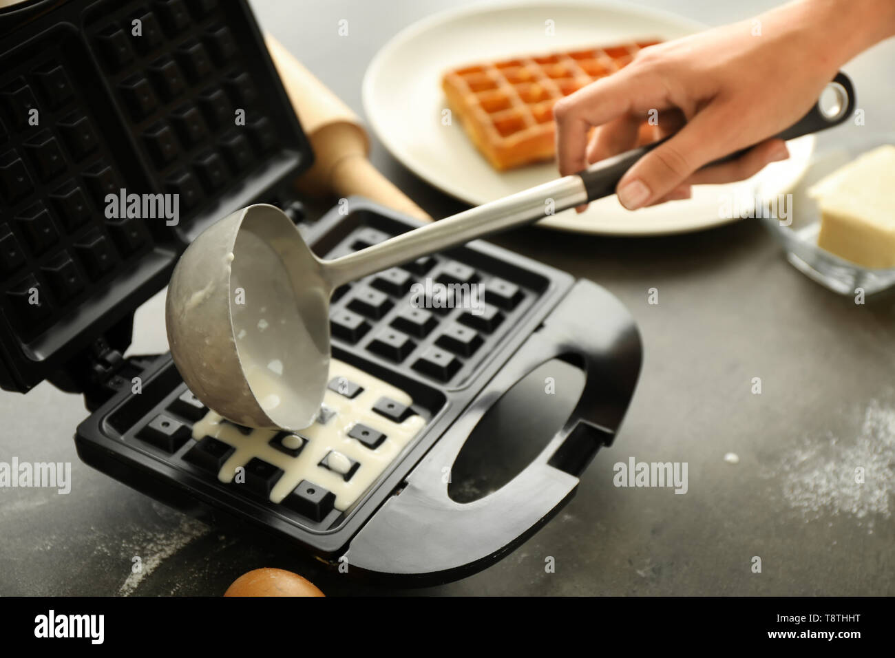 Woman preparing wafers in waffle iron at home Stock Photo Alamy