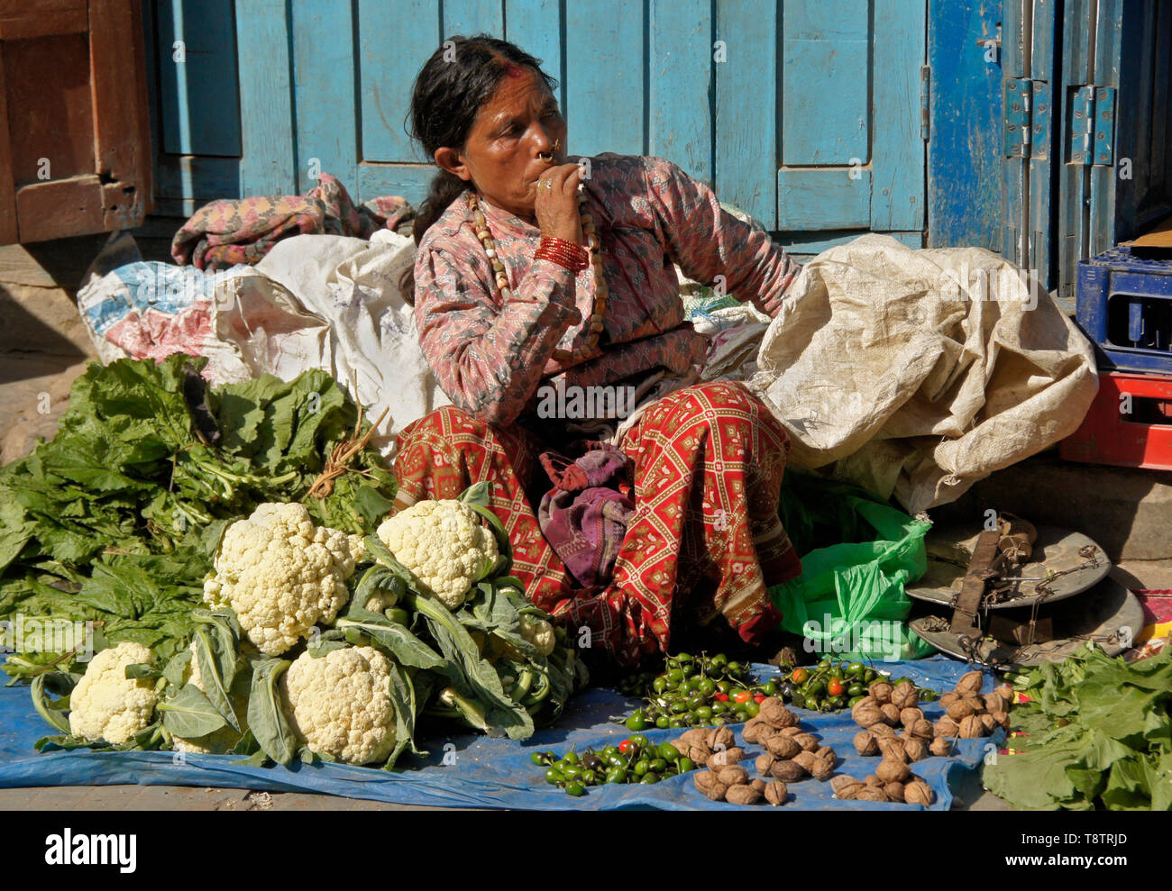 Woman in traditional dress smoking while selling produce in market